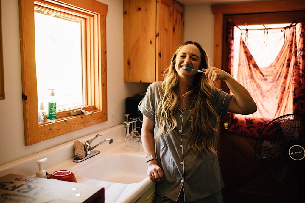 Bridesmaid smiling while brushing her teeth