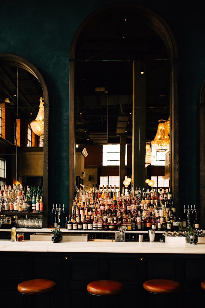 A photo of fully stocked bar with a massive open window behind