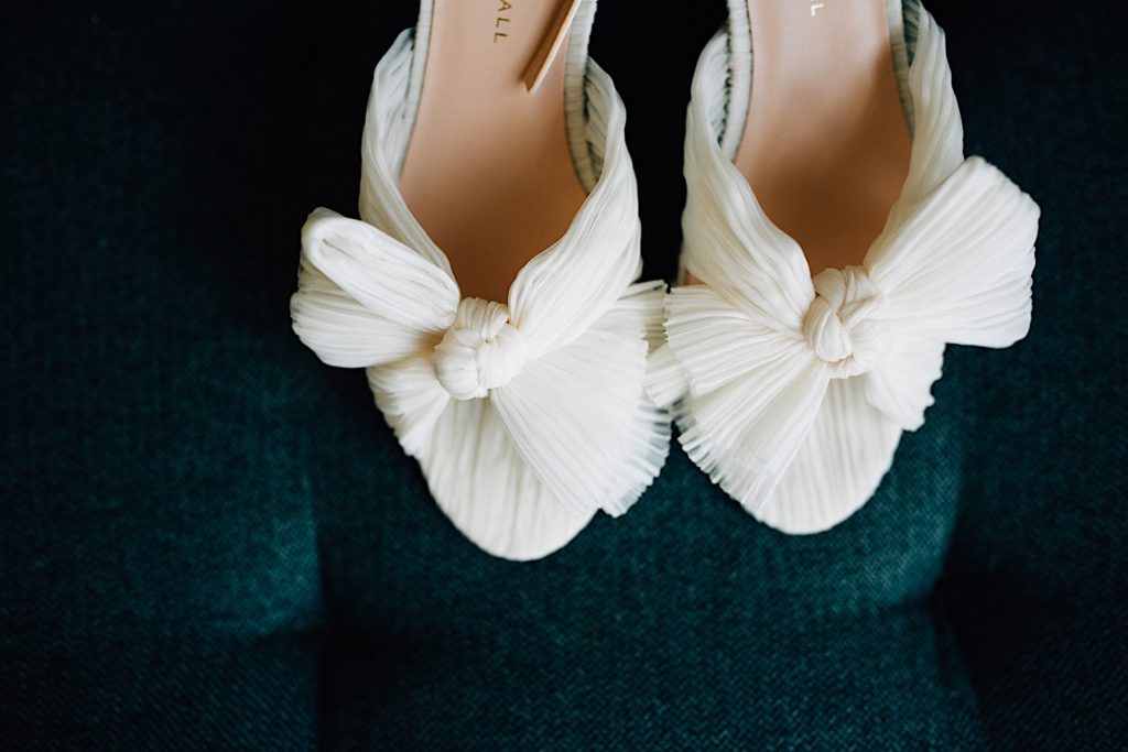 Close up of two white women's shoes on a dark teal cushion 