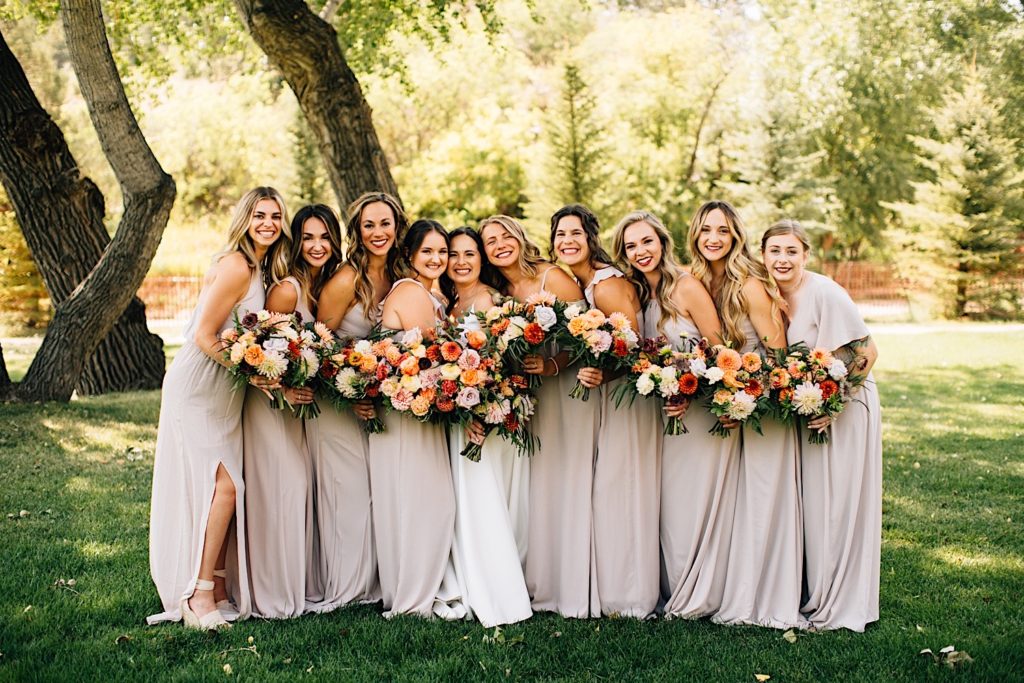 Bride and bridesmaids pose at Planet Bluegrass while holding flower bouquets