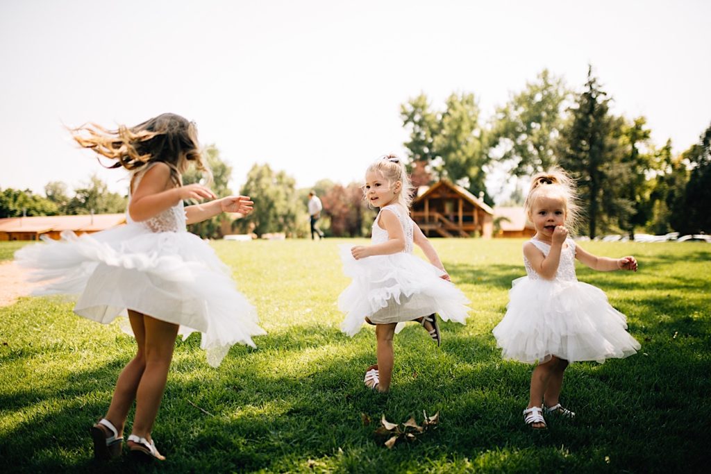 Flower girls in white dresses spin in a field at Planet Bluegrass