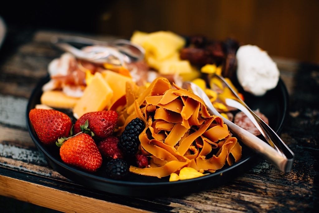 Berries, noodles and other food sitting on a plate with metal tongs