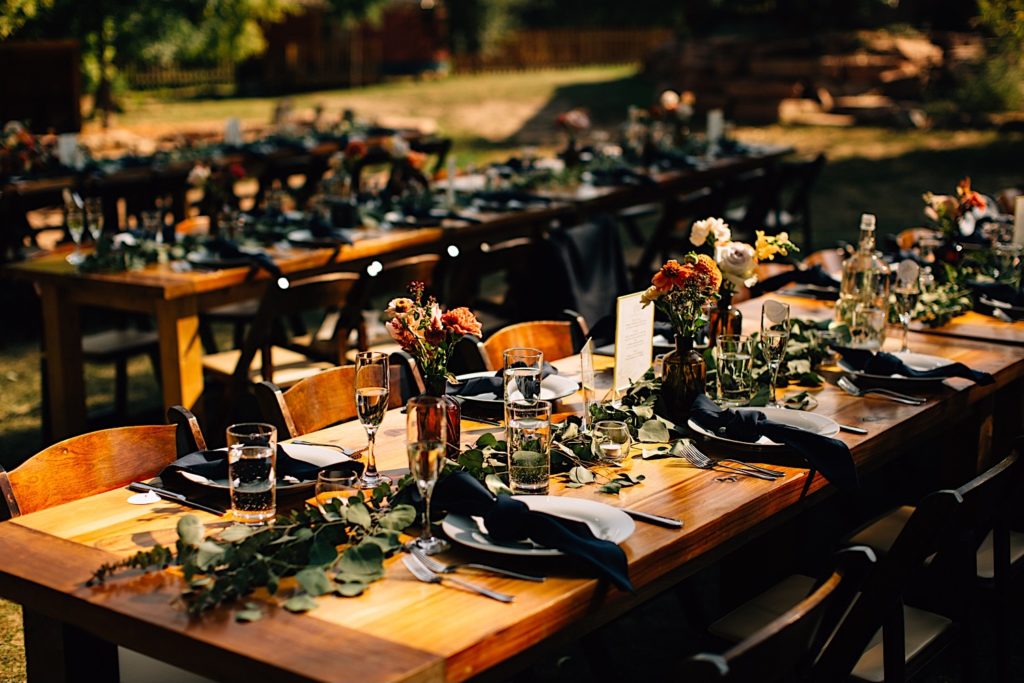 Tables decorated with flowers, glasses, plates and black napkins for a wedding reception at Planet Bluegrass