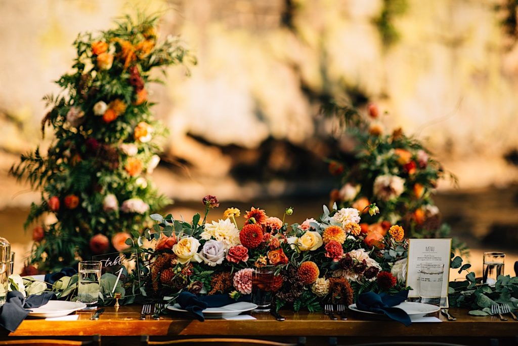 Flowers on a table for a wedding reception at Planet Bluegrass with two flower towers in the background