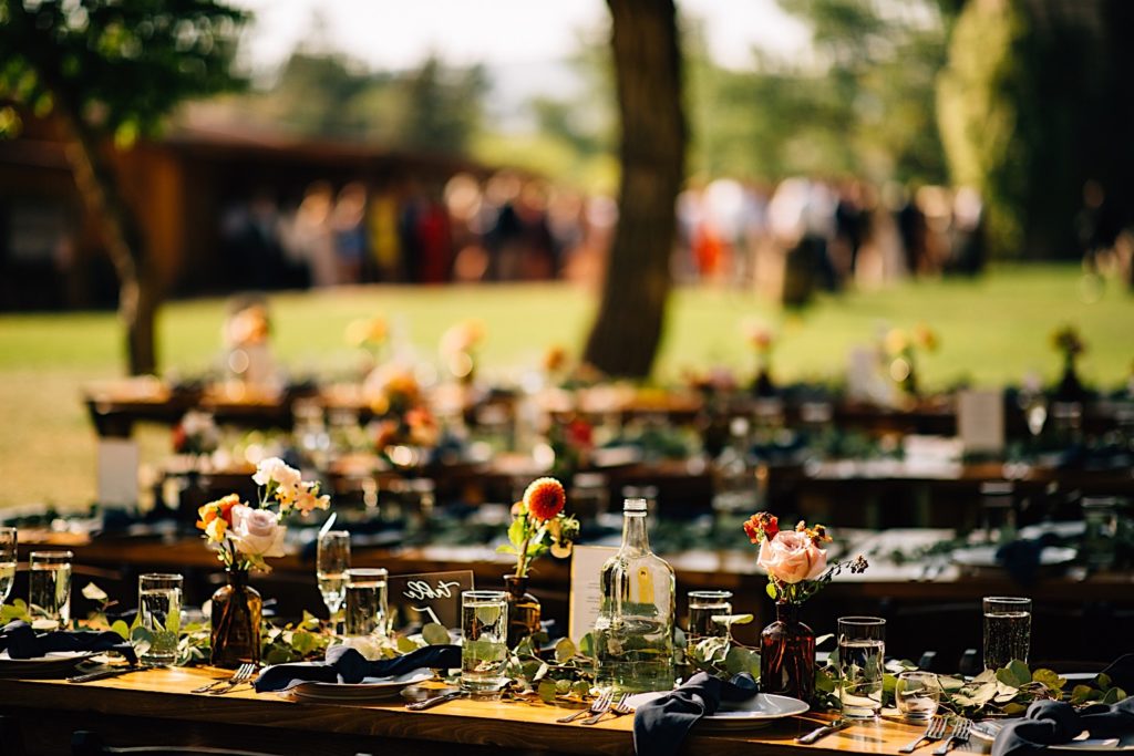 Tables decorated with flowers, glasses, plates and black napkins for a wedding reception at Planet Bluegrass