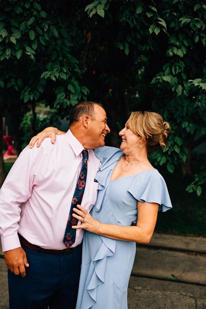 Man and a woman smile at one another during an outdoor wedding reception