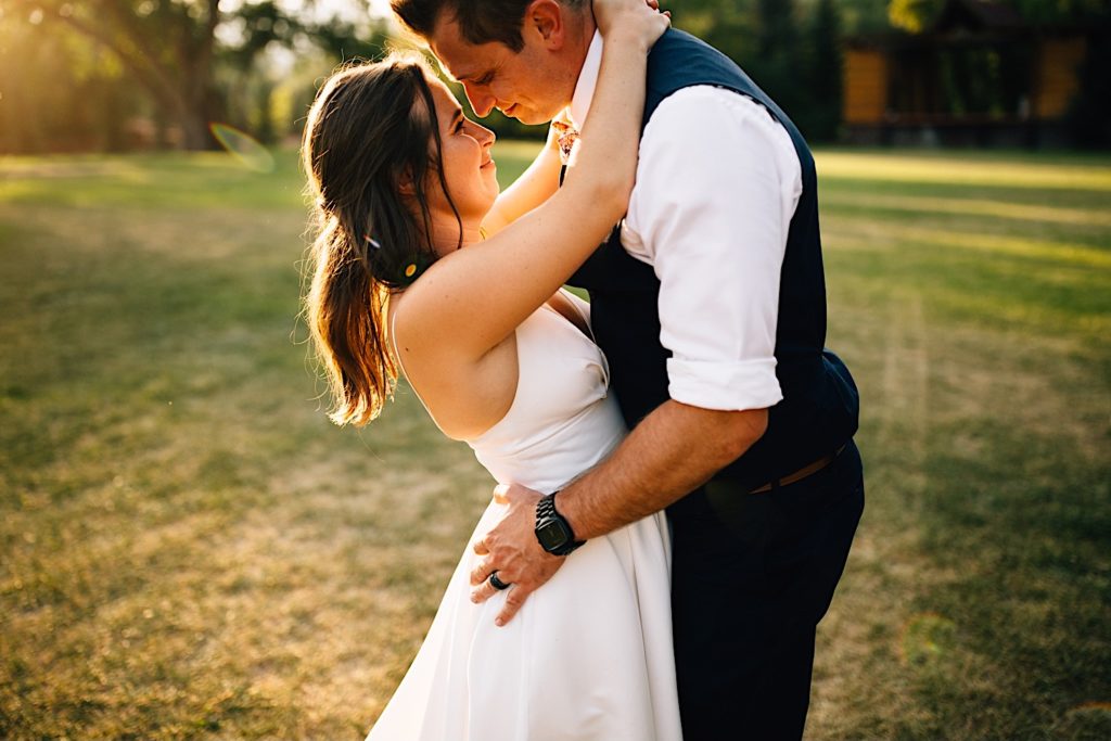 Bride and groom hold each other and smile in a field at Planet Bluegrass after their wedding ceremony