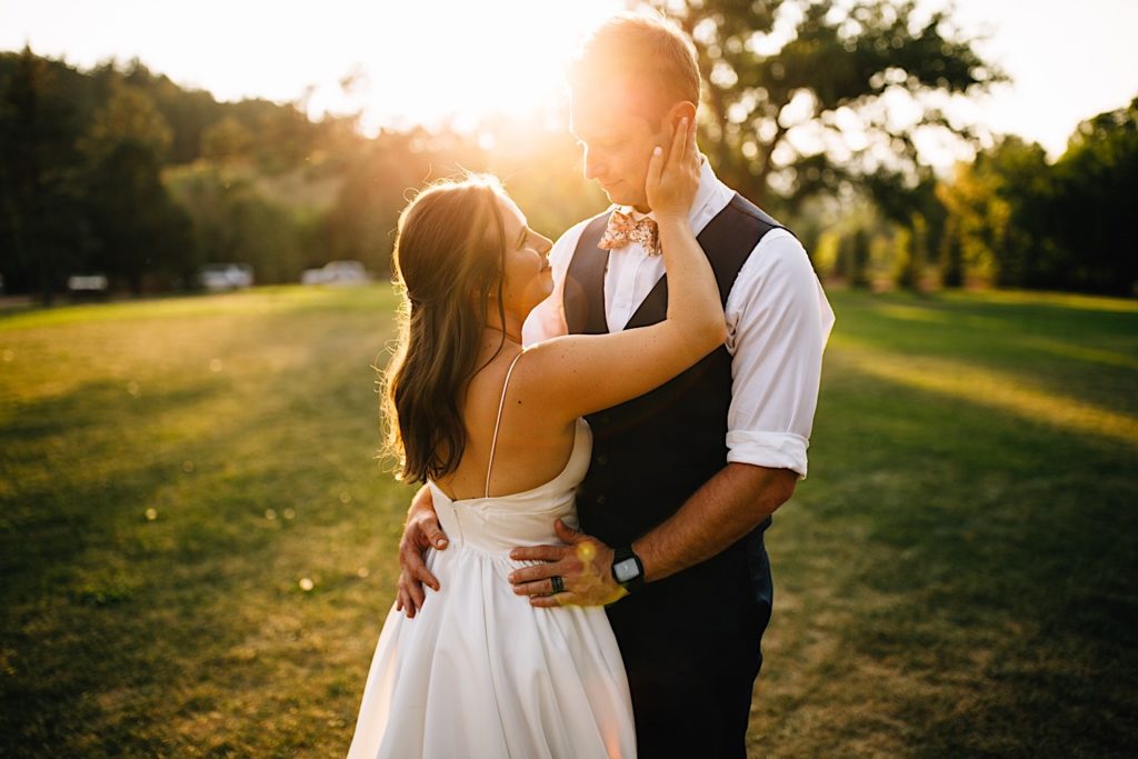 Bride and groom hold each other and smile in a field at Planet Bluegrass after their wedding ceremony