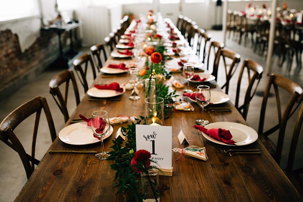 Wooden table set for a wedding reception, it's table 1 and is decorated with plates, wine glasses flowers and cookies at Blanc Denver