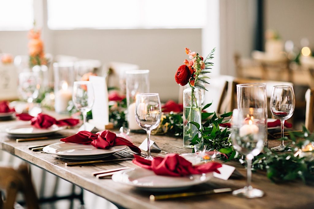 Wooden table set for a wedding reception, it's decorated with plates, wine glasses flowers and cookies at Blanc Denver