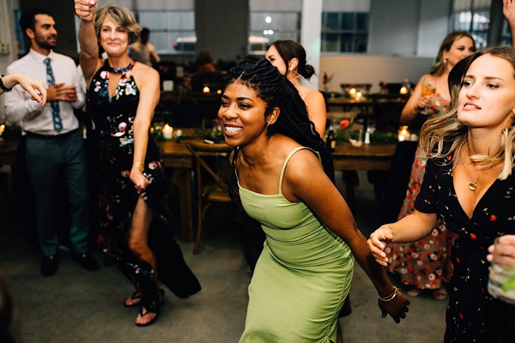 Photo of guests at a wedding reception dancing in a group  