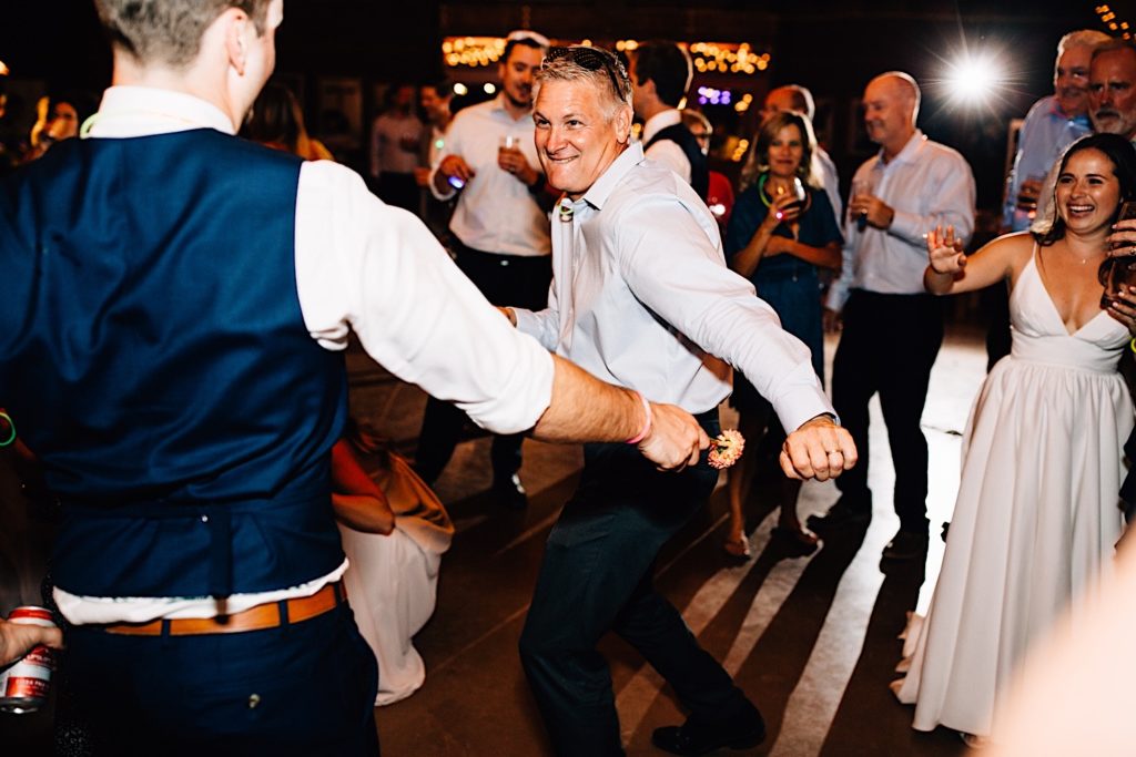 Wedding guests dance and celebrate on the dance floor during a wedding reception at Planet Bluegrass