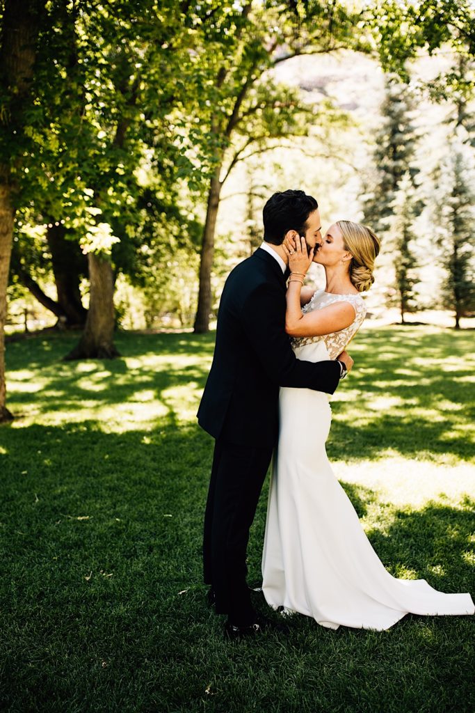 Bride and groom embrace and kiss during their first look the morning of their wedding