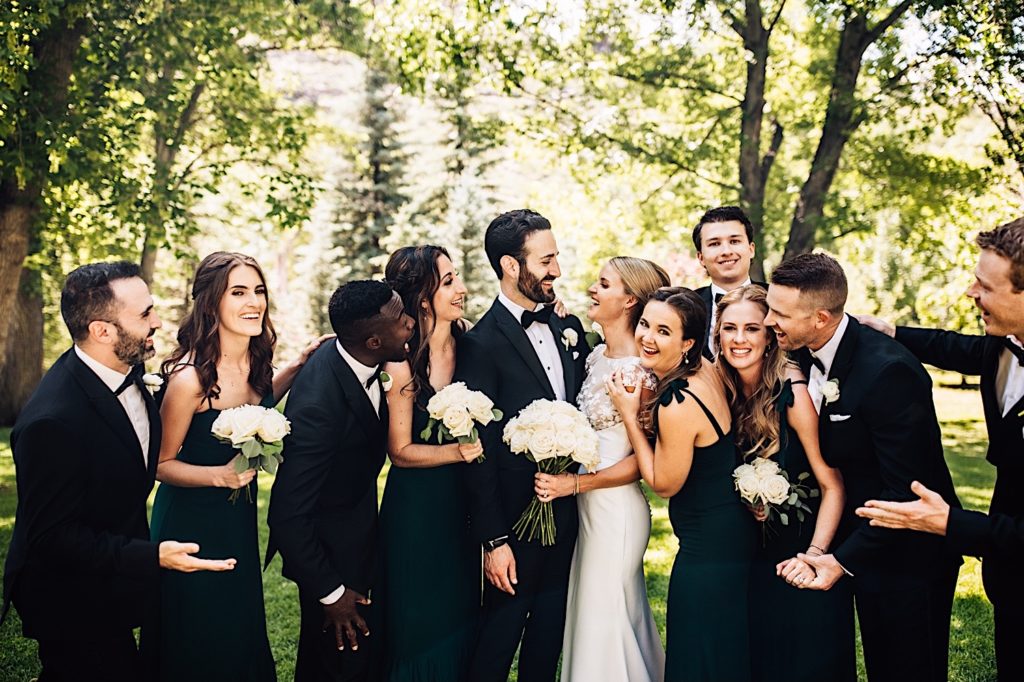 The wedding party snuggles close with the bride and groom smiling and laughing for a photo