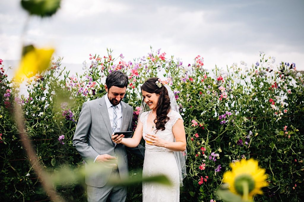 A couple stands in front of a bunch of beautiful wild flowers during their wedding at Lyons Farmette in Lyons Colorado.