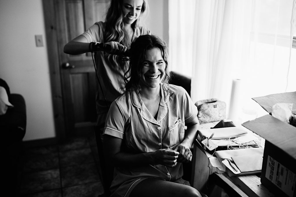 Black and white photo of a bridesmaid smiling while getting her hair done