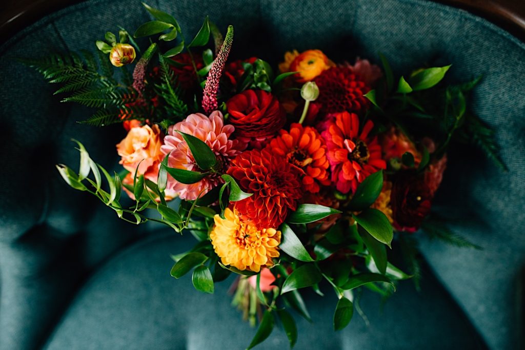 Close up of a bouquet of red, yellow and pink flowers on a dark teal chair
