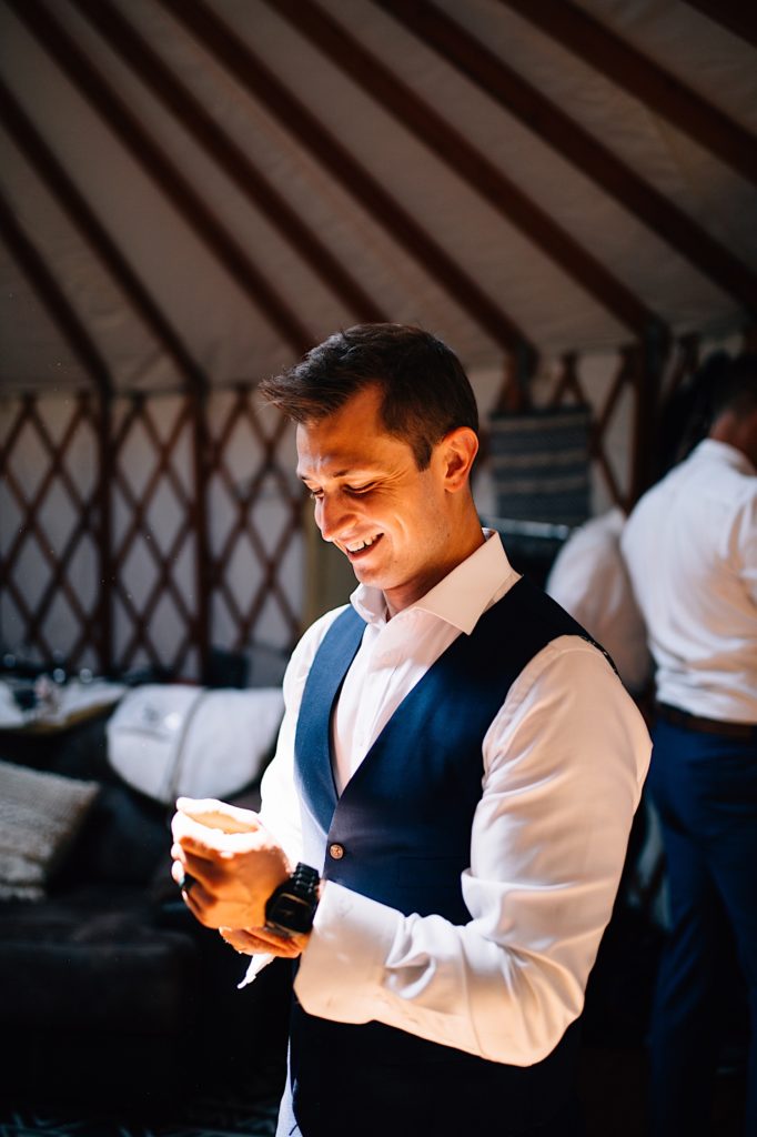 Groom adjusting his watch and smiling