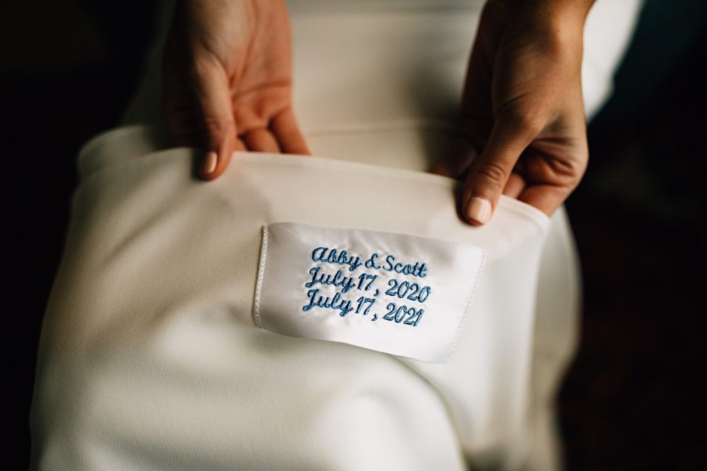 Close up of a label on the inside of a wedding dress that reads "Abby & Scott July 17, 2020 July 17, 2021