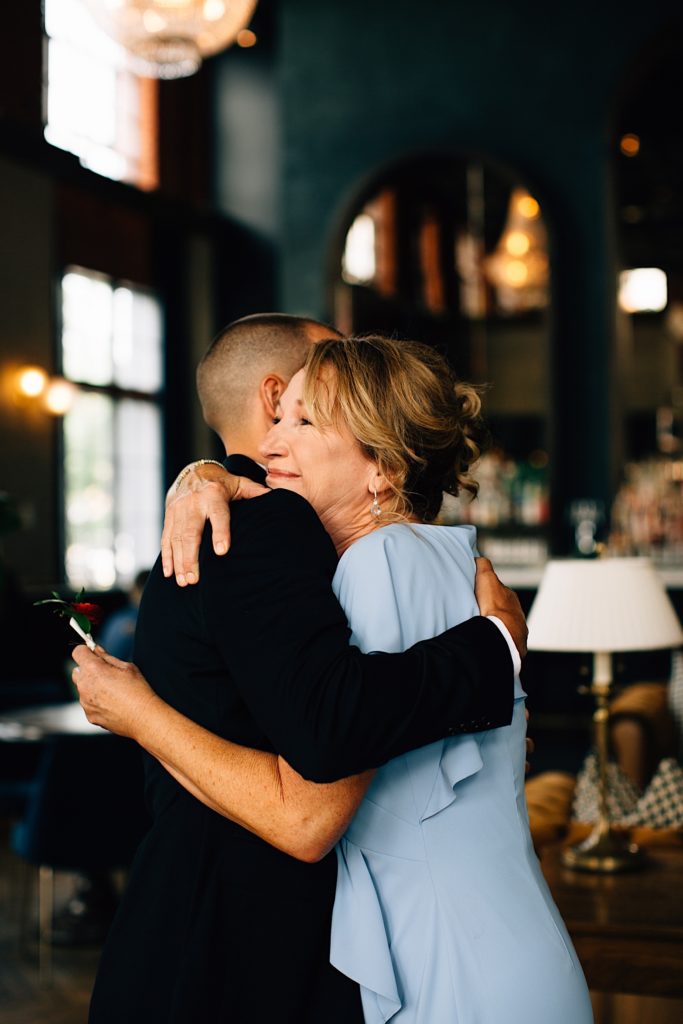 A man and his mother hug inside of a fancy bar before the man's wedding