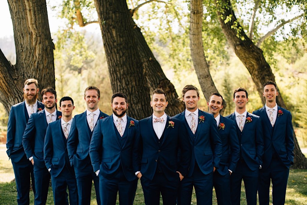 Groom and groomsmen pose at Planet Bluegrass while smiling at the camera