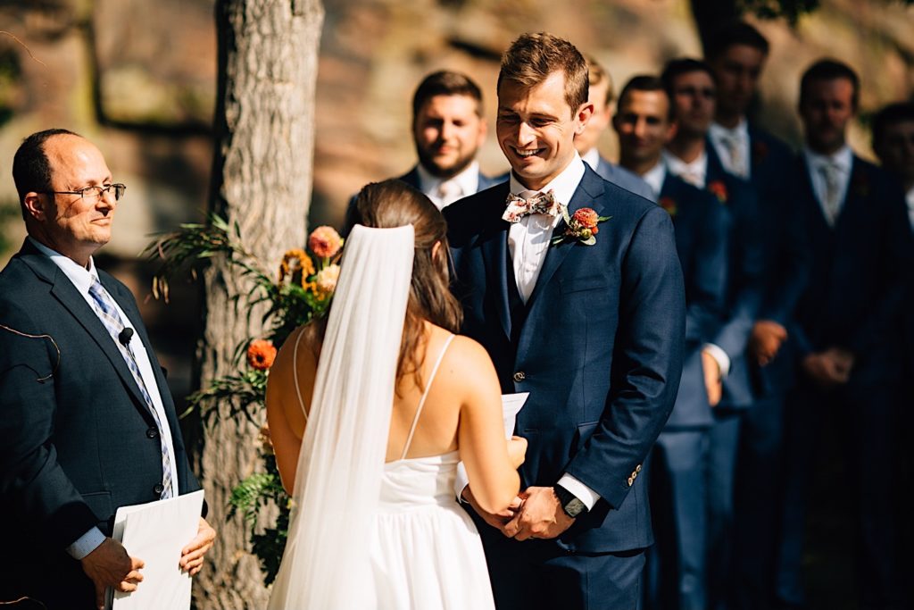 Groom smiles at his bride while she reads her vow to him