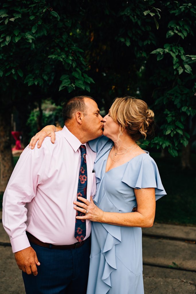 Man and a woman kiss one another during an outdoor wedding reception