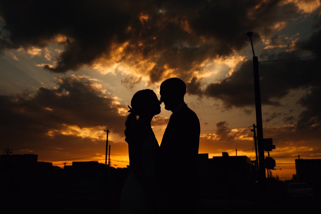 Silhouette  of a man and a woman touching noses together with the sun setting behind them