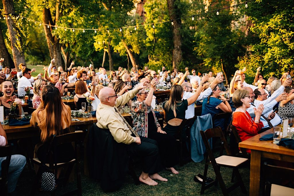 Guests at a wedding reception at Planet Bluegrass all cheer and raise their glasses