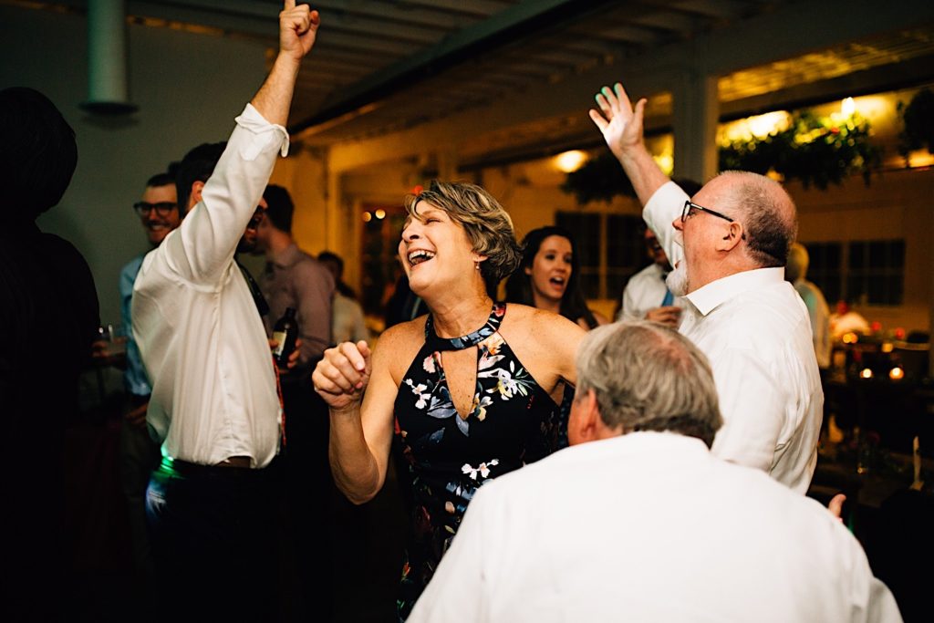 A group of people smiling and dancing at an intimate indoor wedding reception