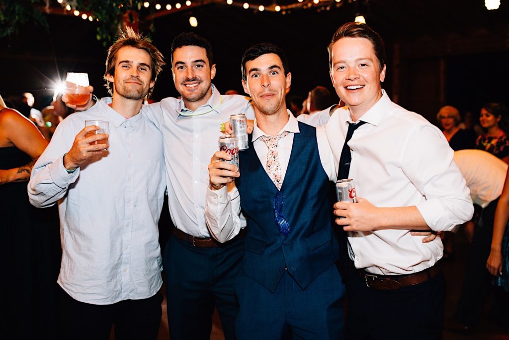 Guests at a wedding reception pose together and smile at the camera while holding their drinks