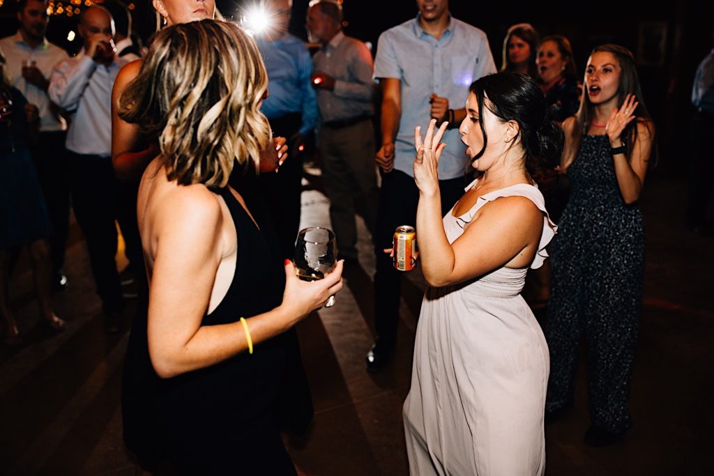 Bride and guests dance on the dance floor while bride shows off her wedding ring