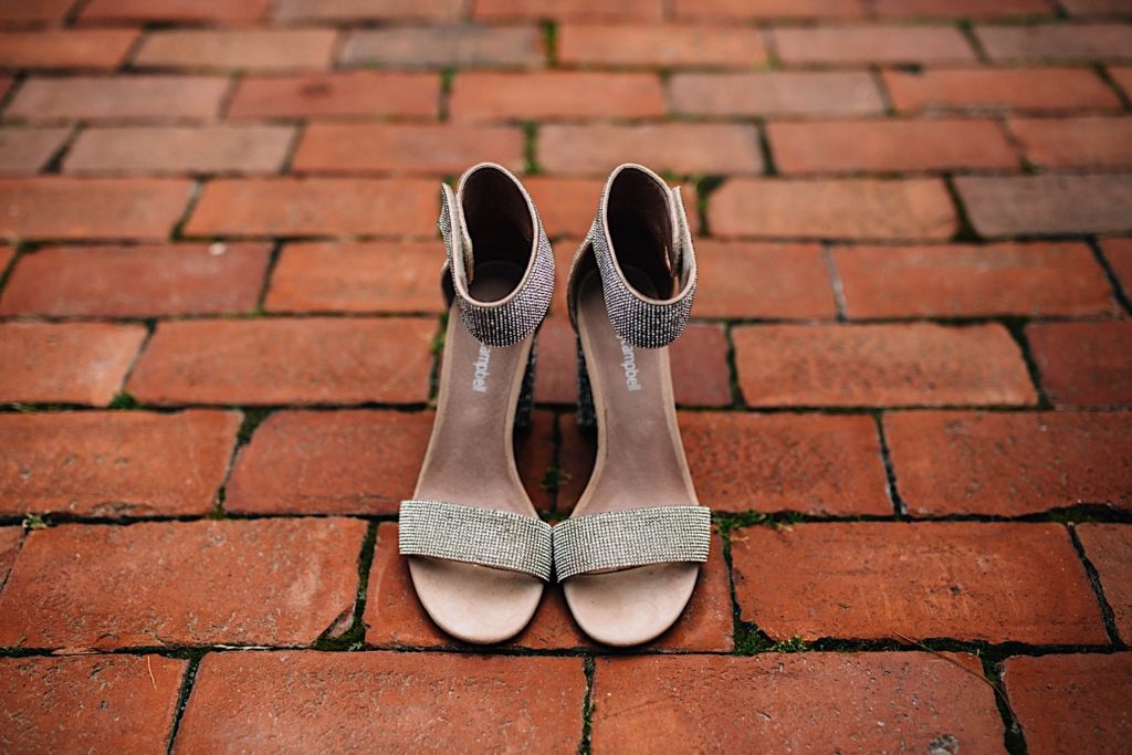 A close up of women's dress shoes on a brick sidewalk.