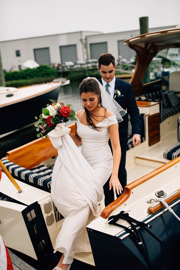 A bride and groom in their wedding attire start to get off a small docked boat after they had photographs taken on the boat.