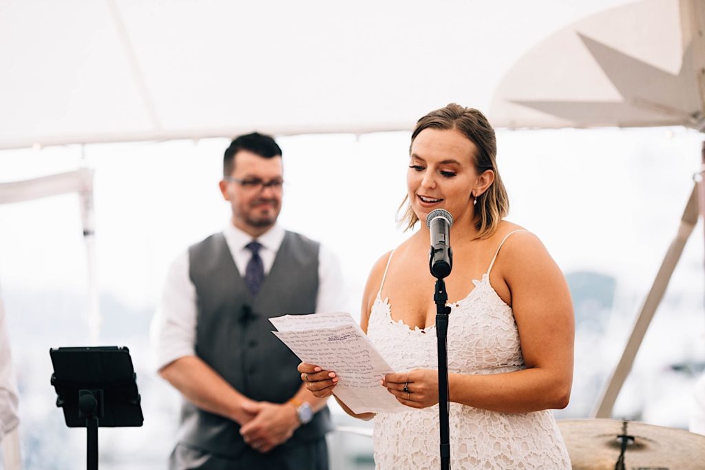 A bridesmaid reads from a paper as she gives a speech during a wedding reception.