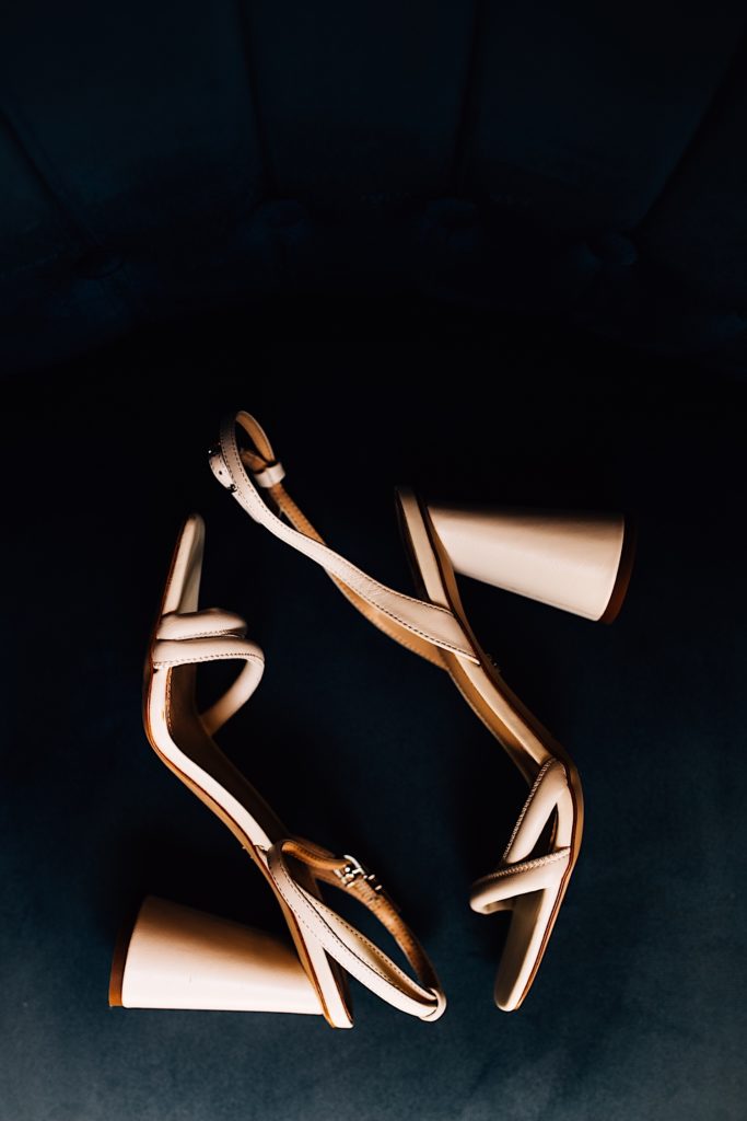 The brides strappy, nude wedding heels sitting on a black suede fabric