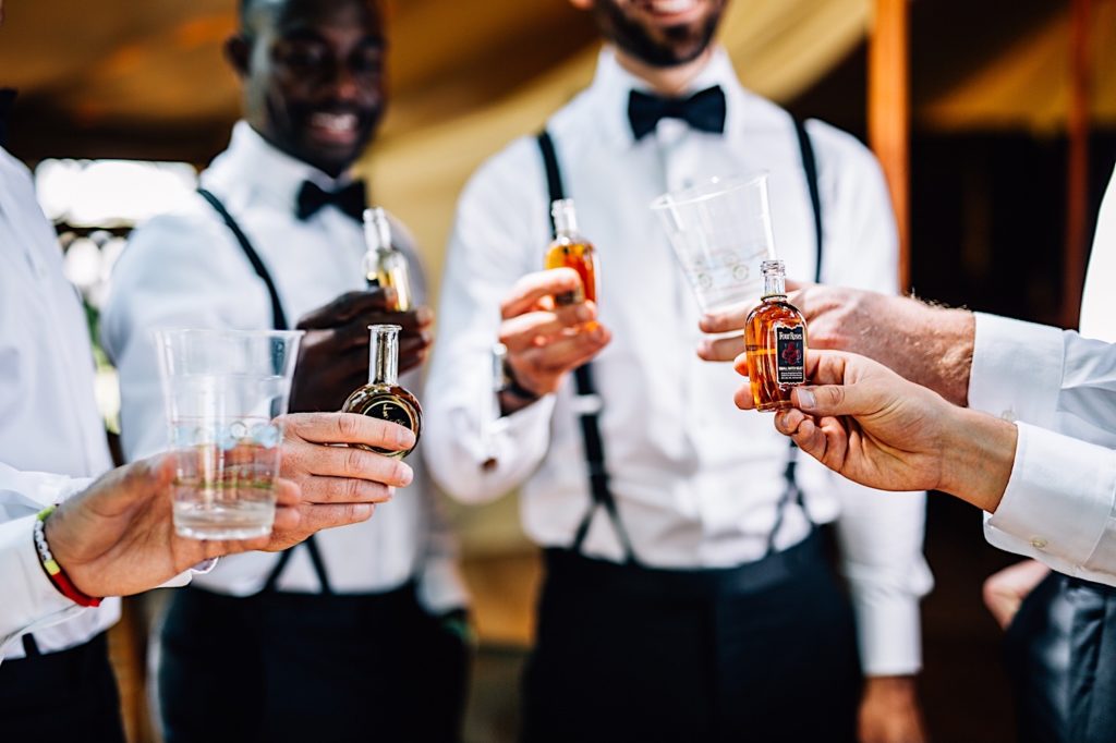 Groom and groomsmen share toasts and mini bottles of fireball.