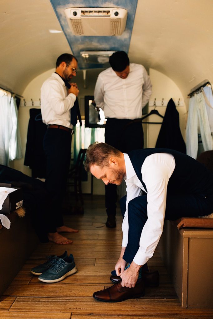 A groom gets ready with his groomsmen in a vintage airstream at their Colorado wedding venue.